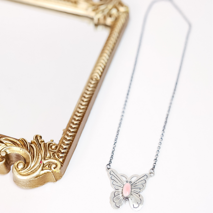 Butterfly necklace with pink center on a white background