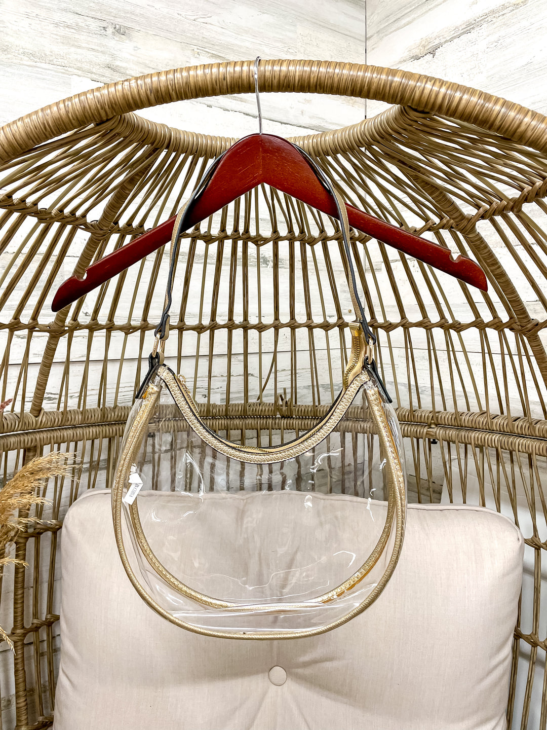 Clear stadium with gold trim hanging from a wicker chair on a hanger. 