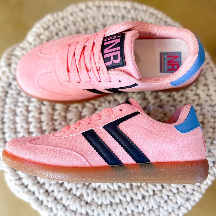 Pink sneakers with black and blue accents on a woven surface
