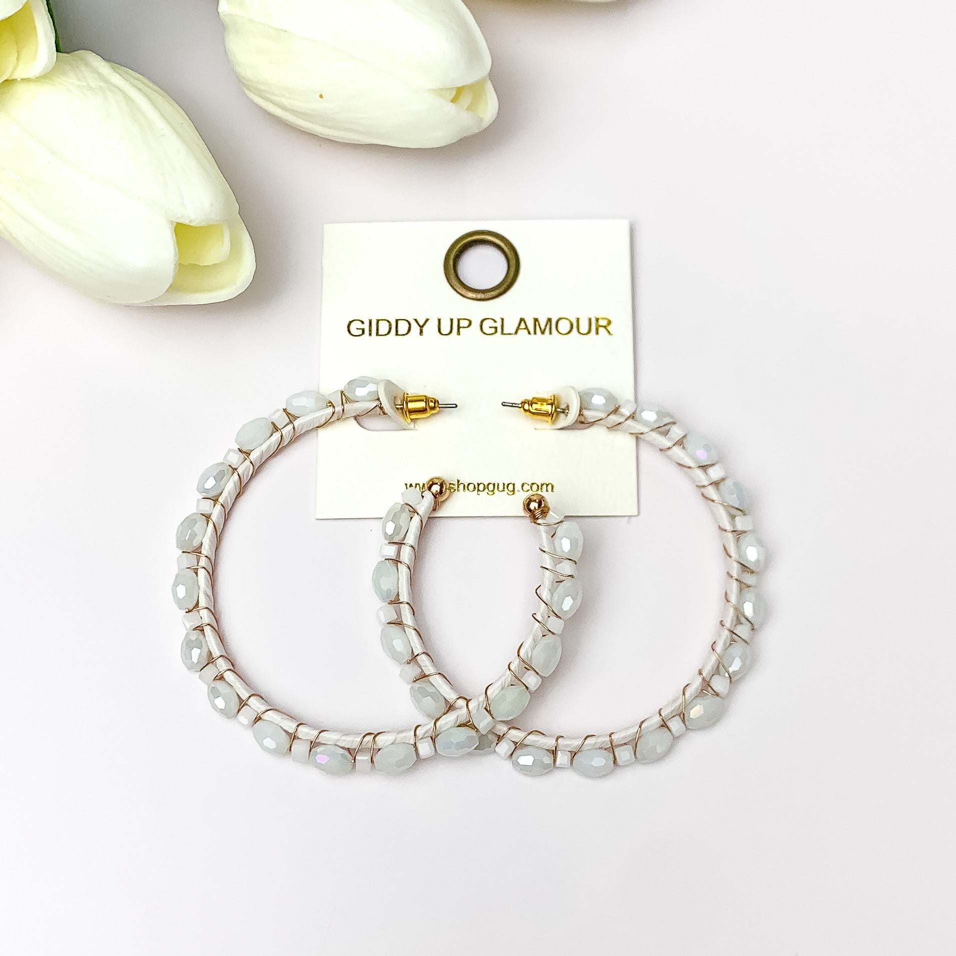 Large Hoops Outlined with Crystals in White. Pictured on a white background with white flowers in the top left corner.
