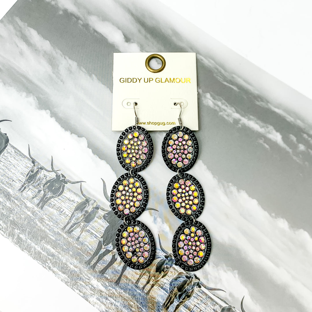 Three tier black oval shape dangle earrings with ab crystals. Pictured on a black and white western picture.