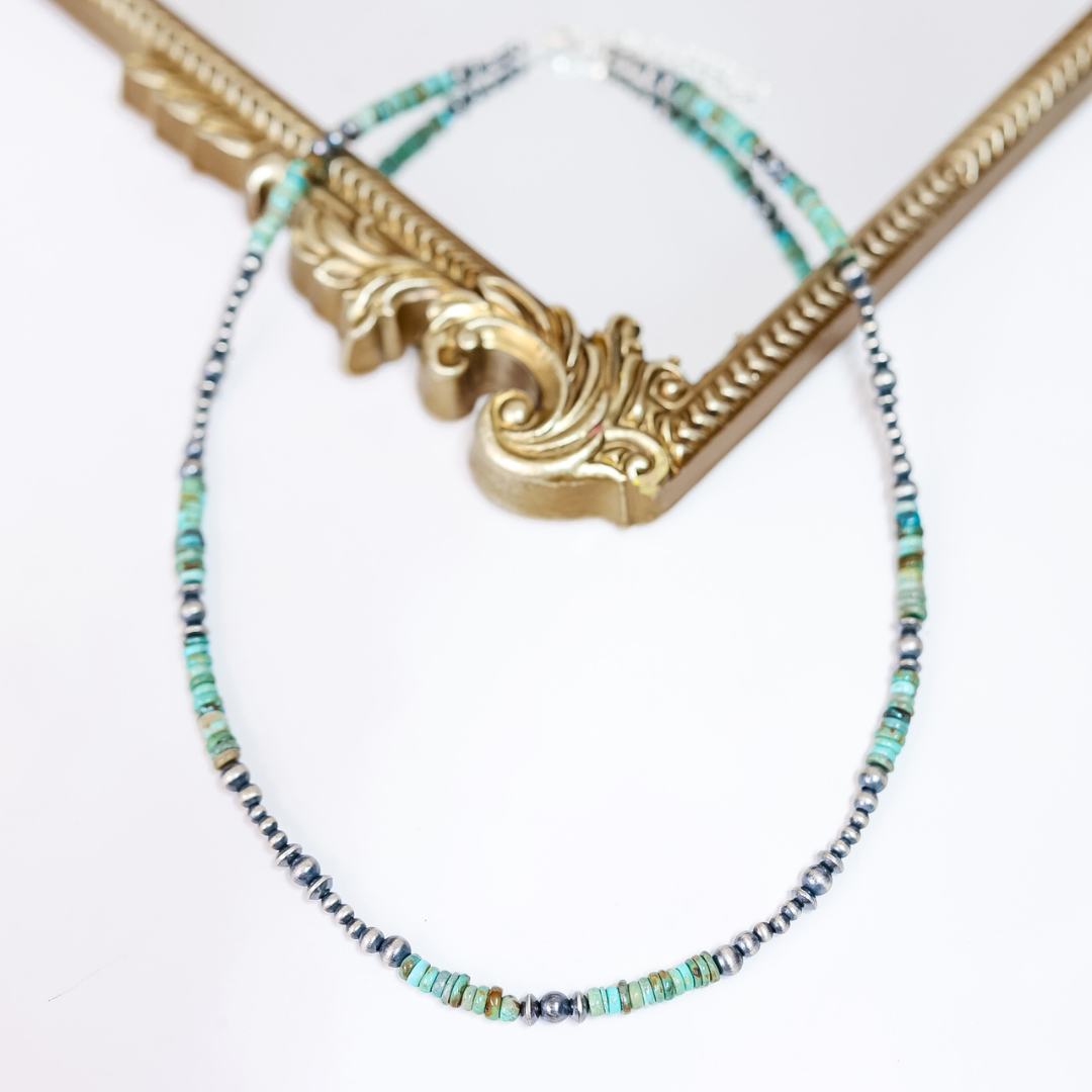 Handmade Red River Turquoise and Sterling Silver Navajo Pearl necklace styled flat with ornate gold frame; 22-inch length with 2-inch extender.