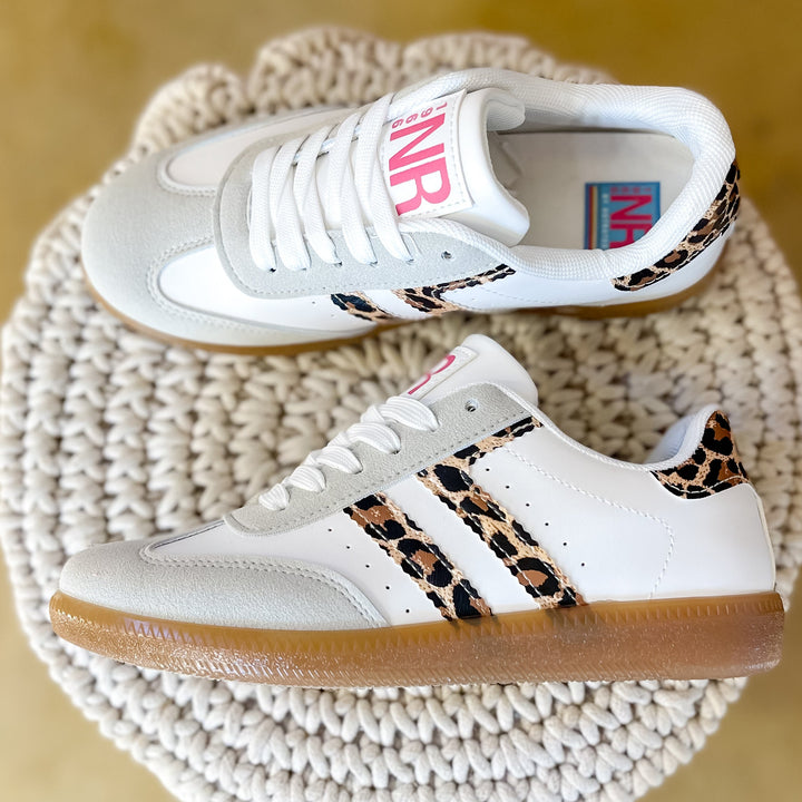 White sneakers with leopard print accents on a woven stool.