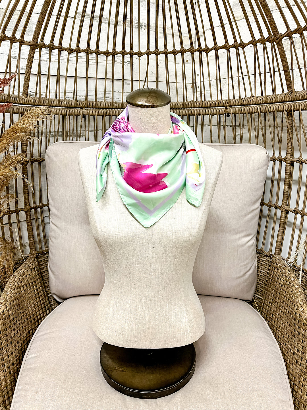 Mannequin head with a colorful scarf on a chair against a wicker background