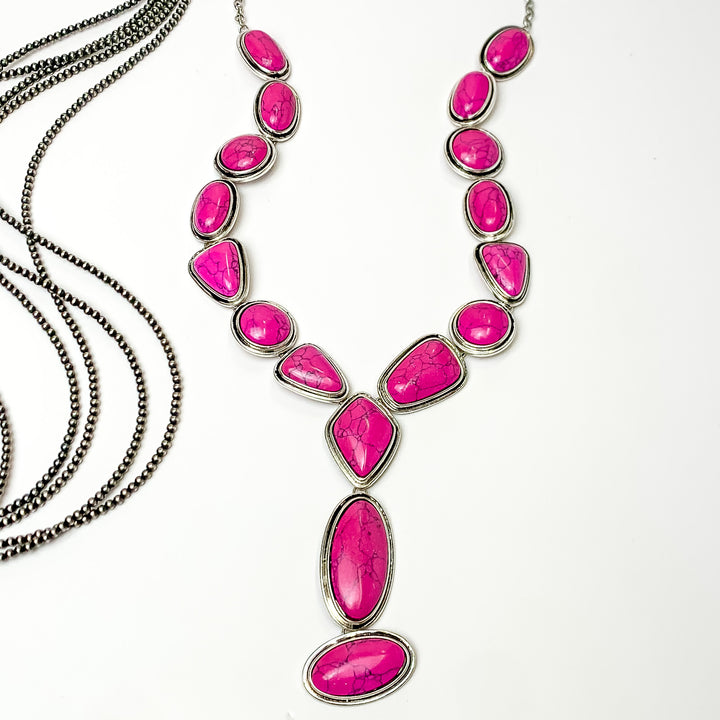 Multi stoned long necklace in pink with a dangling pink stones. Pictured on a white background with Navajo pearl stands.