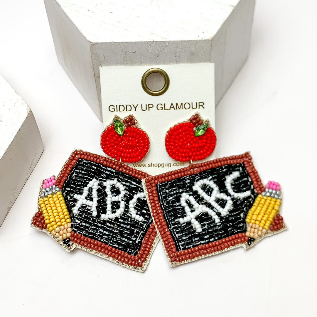 ABC Chalkboard Beaded Earrings With Red Apple Posts. These earrings are on a white background and have white posts around them.