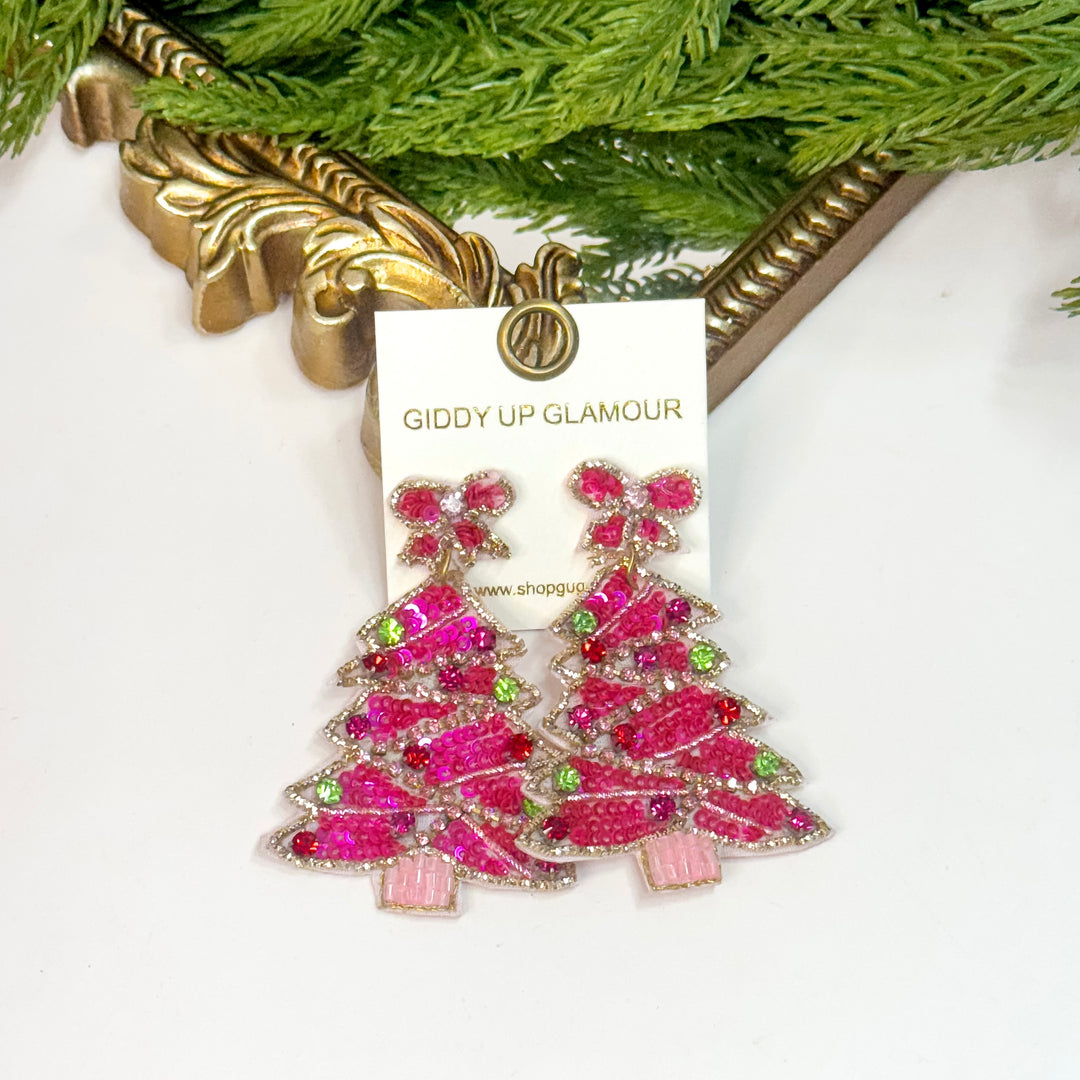 Pink Christmas tree earrings on a Giddy Up Glamour card with greenery in the background