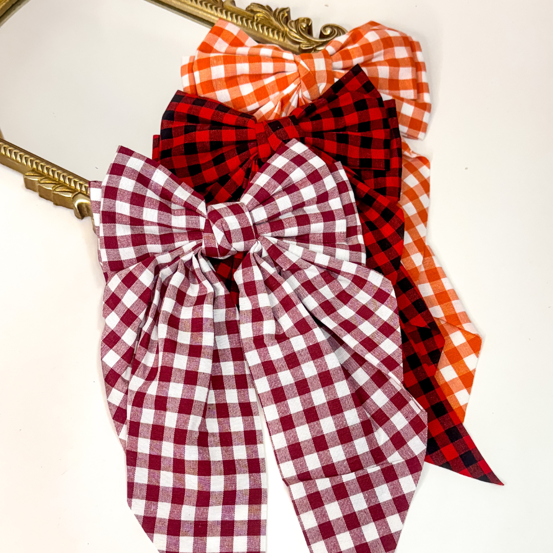Oversized gingham hair bows 🎀 in maroon & white, red & black, and orange & white. Trendy gameday accessory with clip backing.