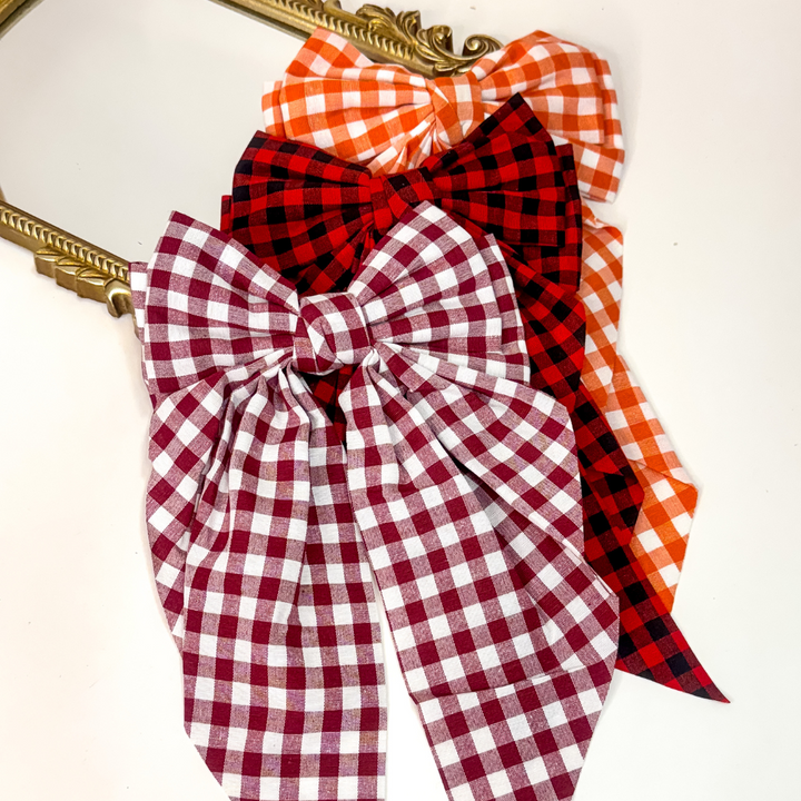 Oversized gingham hair bows 🎀 in maroon & white, red & black, and orange & white. Trendy gameday accessory with clip backing.
