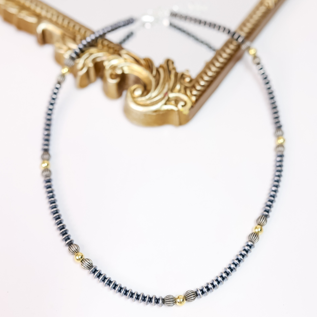 Hand-strung Navajo pearl necklace with 7mm saucer beads, ribbed sterling silver accents, and 14K gold-plated beads. 20-inch necklace with 2-inch extender.