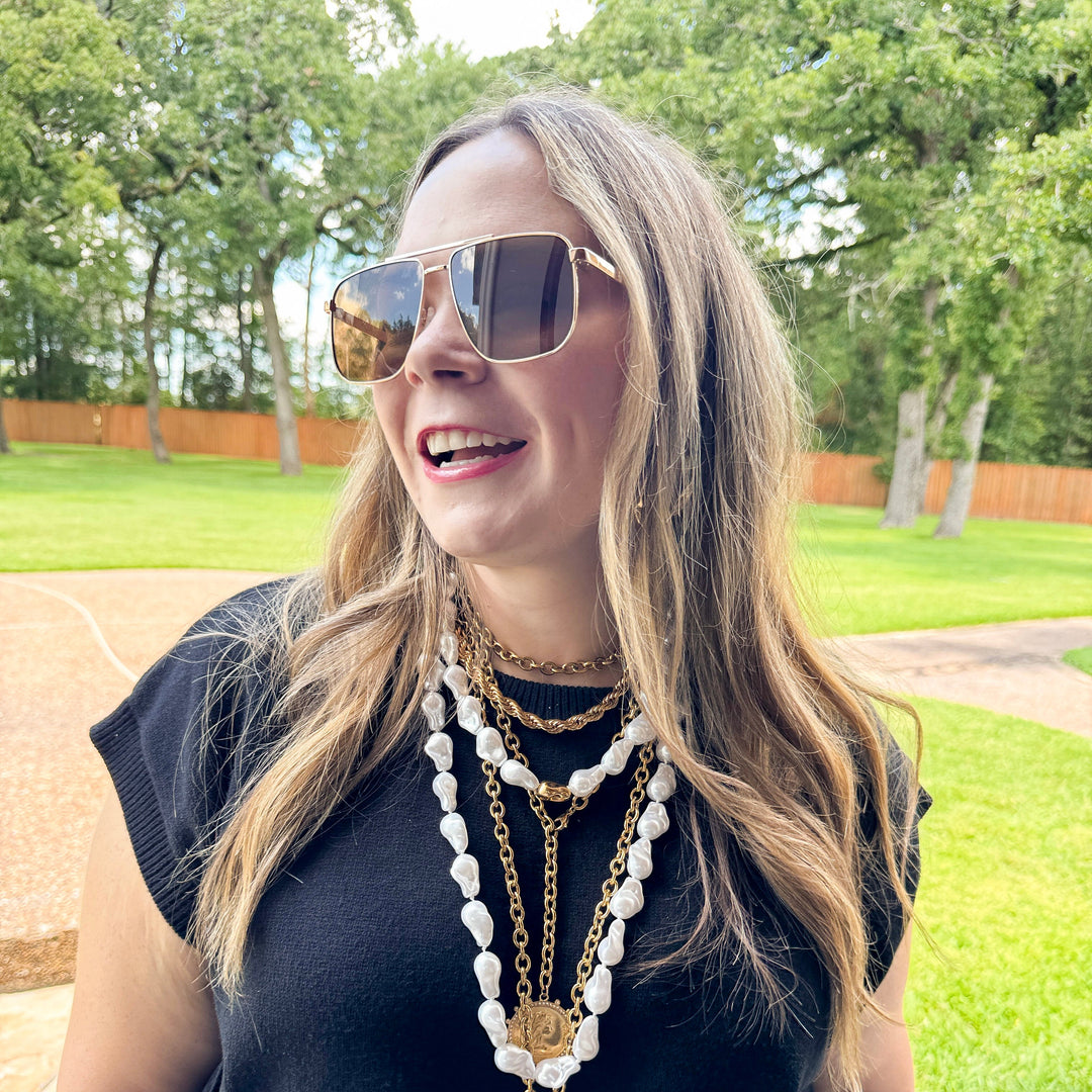 Woman wearing sunglasses and a long necklace outdoors