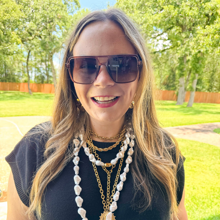 Woman wearing sunglasses and multiple necklaces outdoors