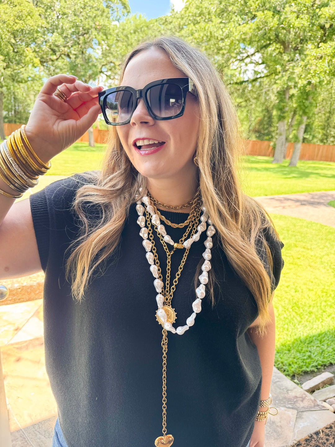 Woman wearing sunglasses and layered necklaces outdoors
