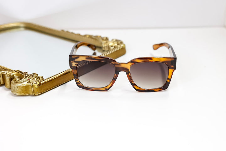 Tortoiseshell sunglasses with gold chain on a white background