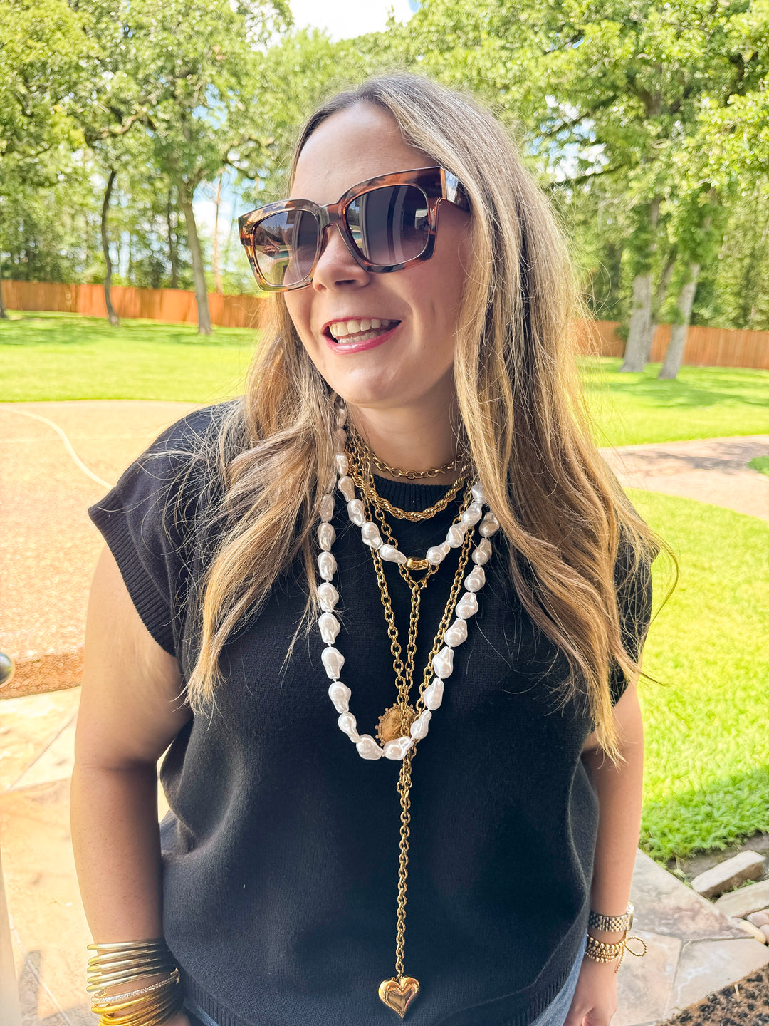 Woman wearing sunglasses and layered necklaces outdoors