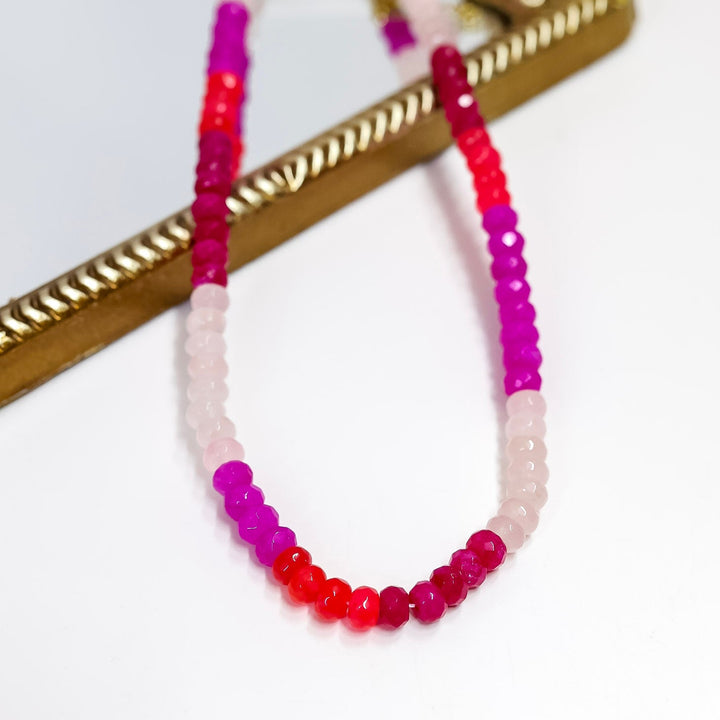 Beaded necklace with pink and red beads on a white background