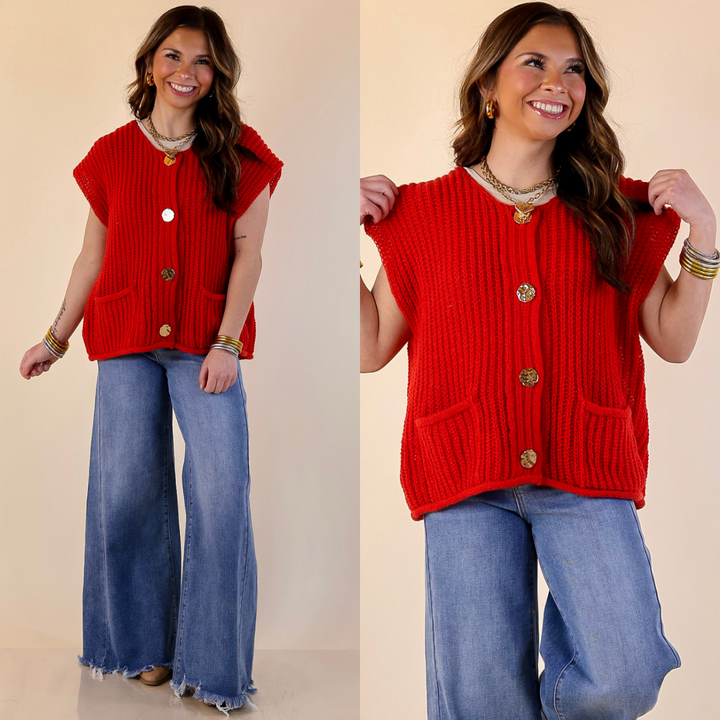 Woman wearing a red knitted vest with gold buttons and blue jeans on a beige background