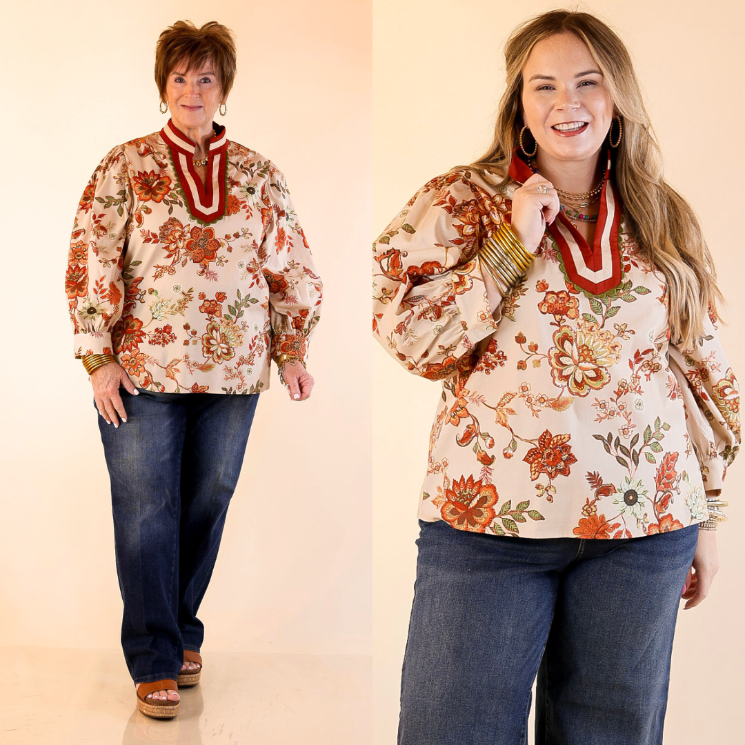 Models are wearing floral long sleeve top with trim in rust orange and blue jeans with a plain background