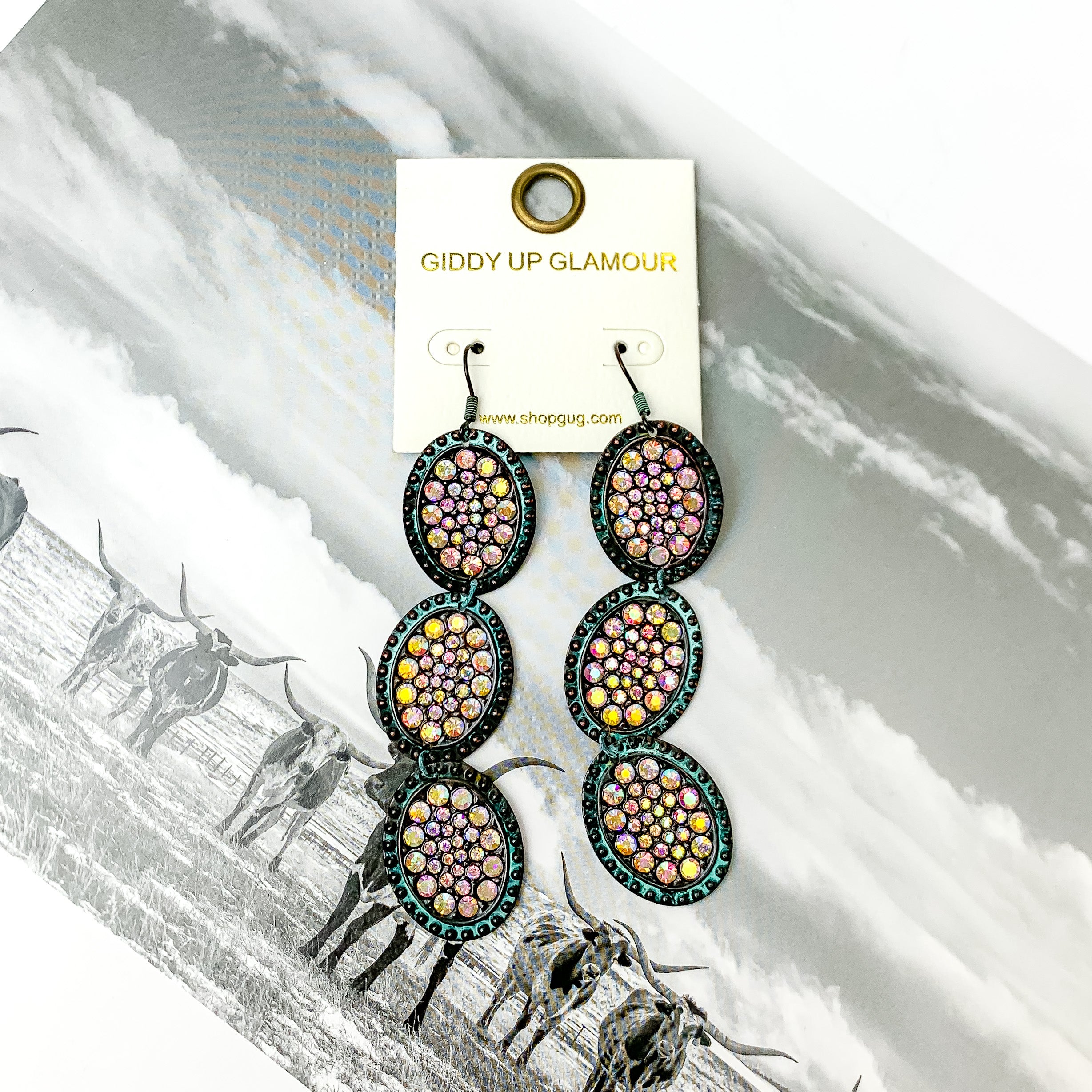 Three tier patina and ab crystals oval shape dangle earrings with ab crystals. Pictured on a black and white western picture.