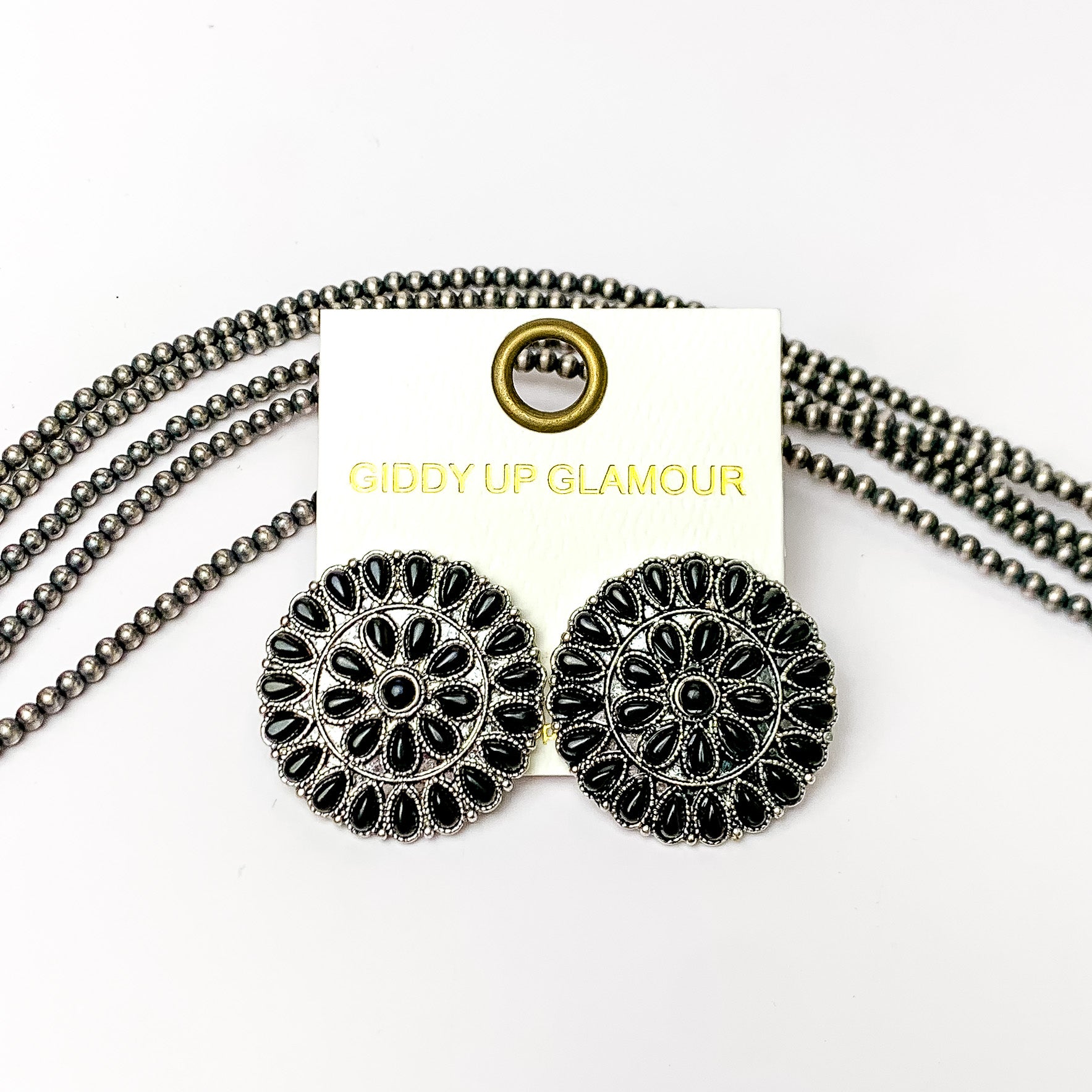 Silver Tone Circle Cluster Stud Earrings with Black Stones. Pictured on a white background with beads through the background.