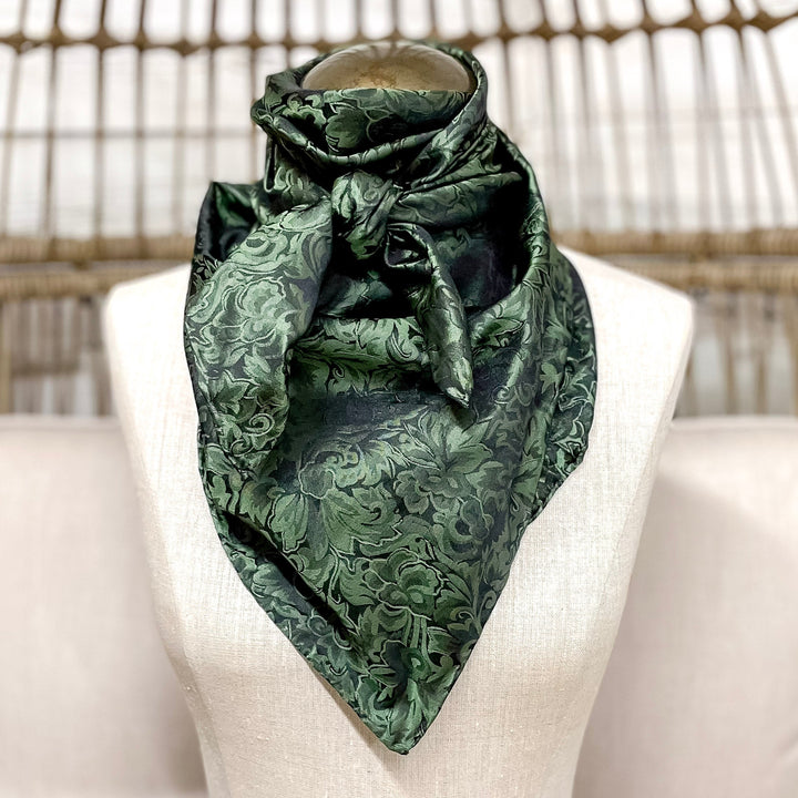 Green patterned scarf on a mannequin head against a wicker chair background
