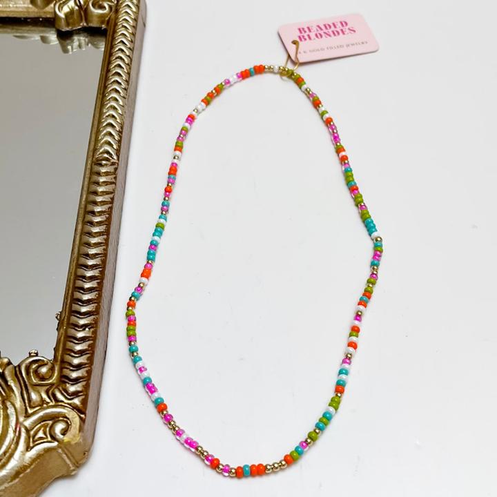 Colorful beaded necklace on a white background with a gold frame.