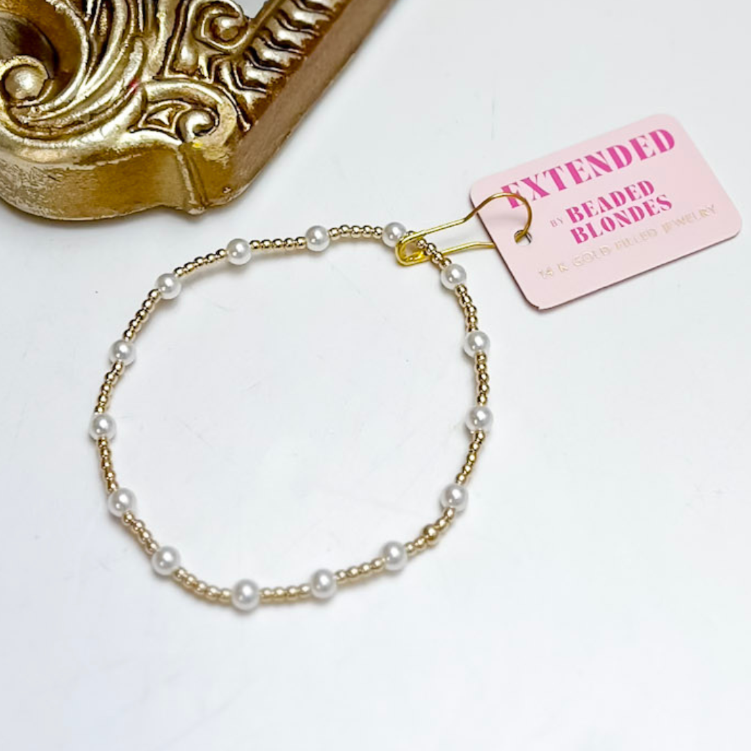 Pearl bracelet with gold accents on a white background, featuring a brand tag.