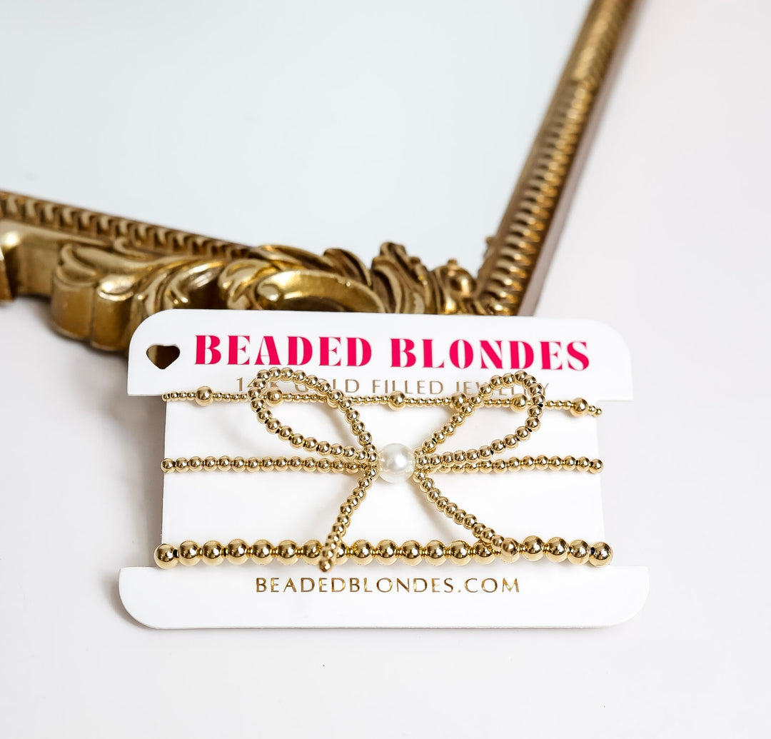 white background with gold framed mirror showing three Beaded Blondes bracelet set including a bow with a pearl center as well as a mix size bracelet and a 5mm bracelet all made in United States