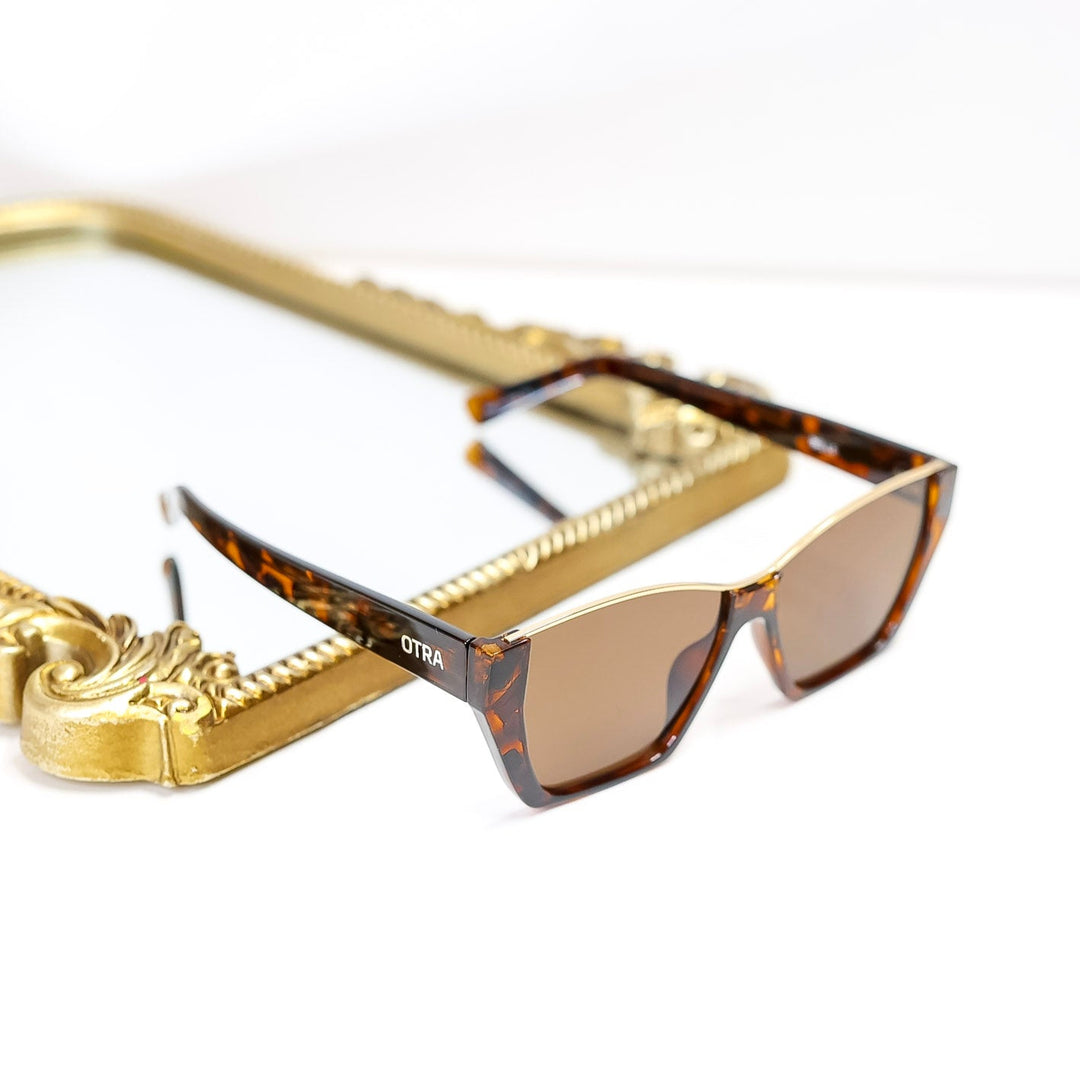 Sunglasses with gold frame and tortoiseshell pattern on a white background