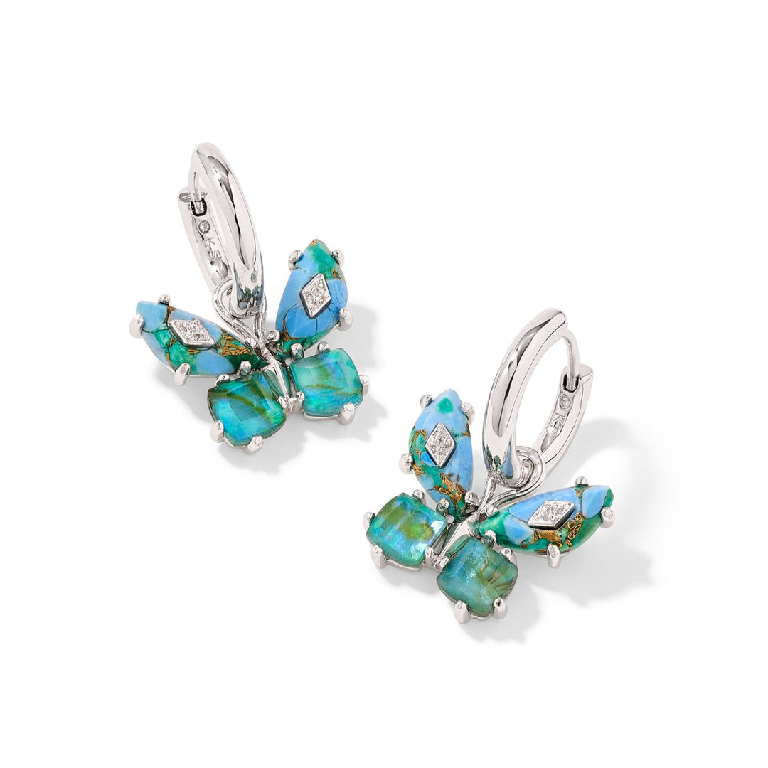 On a solid white background. silver huggie earrings in a aqua blue mix