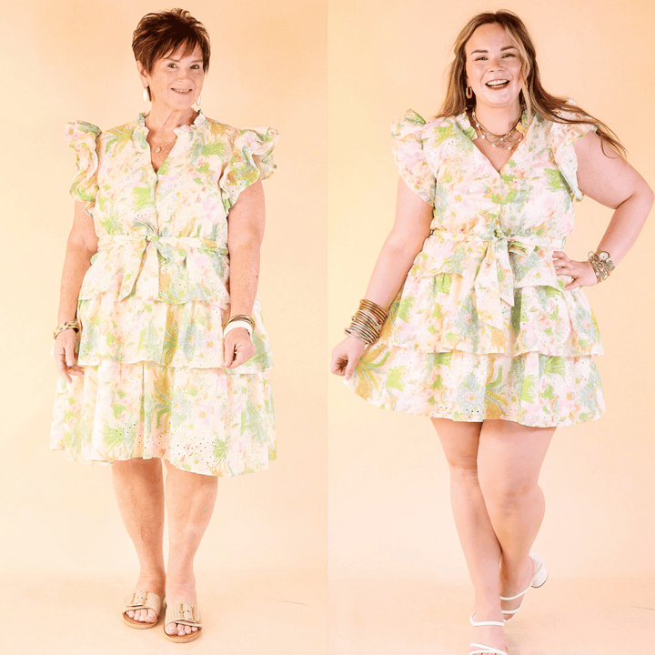 Blooming in Bows dress features a V-neckline, ruffle sleeves, a bow-tied waist, and a tiered skirt with floral eyelet detailing. Sizes small through plus sizes.