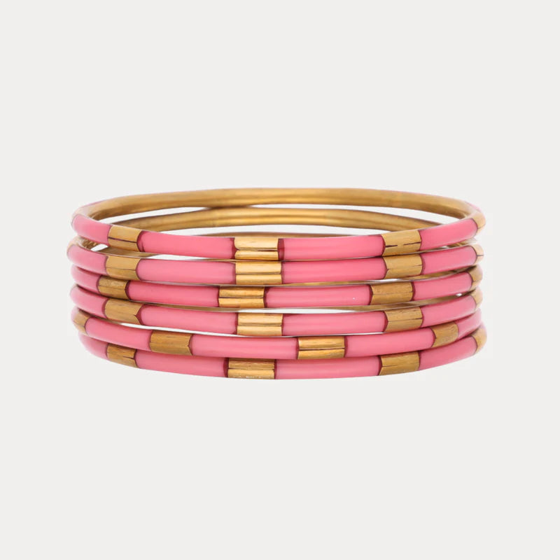 Set of pink and gold bangles on a light gray background