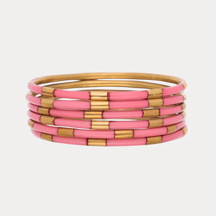 Set of pink and gold bangles on a light gray background