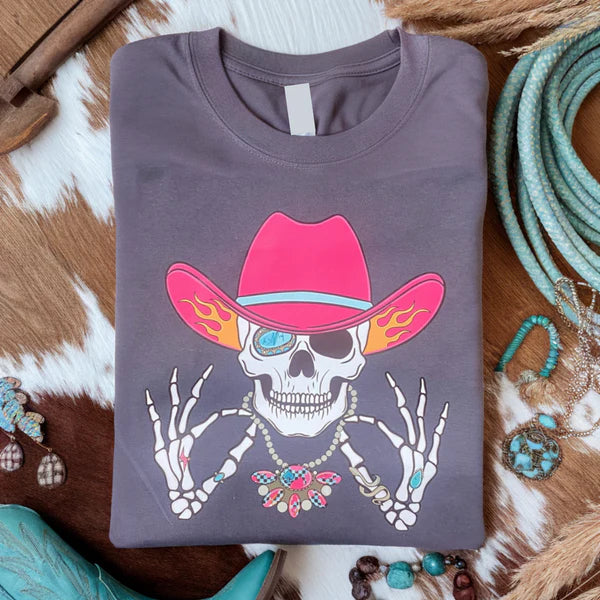 Gray t-shirt with a colorful skeleton wearing a pink cowboy hat on a rustic background.