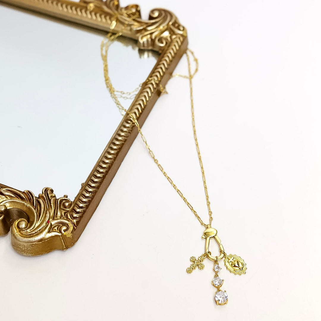 Gold necklace with a pendant on a white surface with a decorative gold frame.
