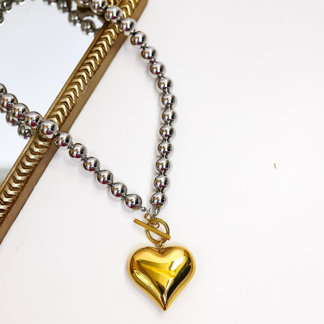 Gold heart-shaped pendant on a chain against a white background