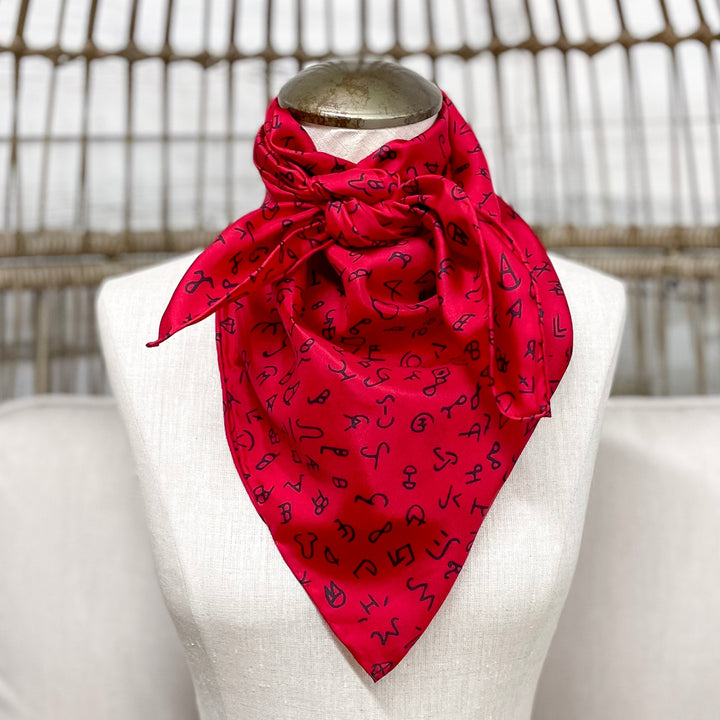 Red patterned scarf on a mannequin bust against a wicker chair background