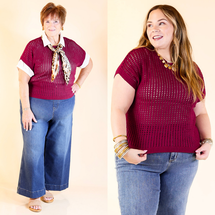 Two women wearing matching maroon short-sleeve sweater tops and blue jeans against a plain background.