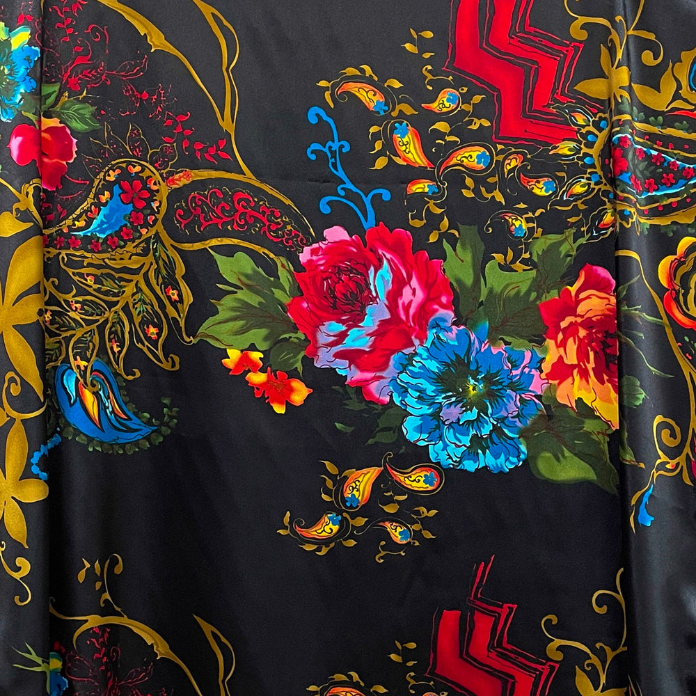 Decorative black wild rag with colorful floral patterns draped over a wicker chair.