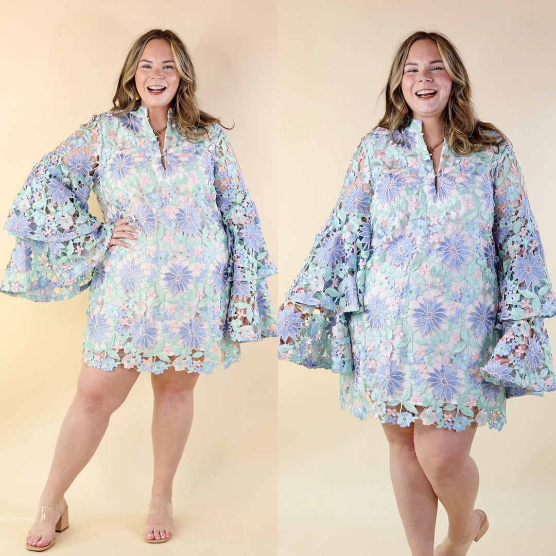 This dress features a mix of green, blue, and pink pastels, a deep V-neckline, elegant bell sleeves, and three buttons up the front for a secure fit. Sizes small to XL.
