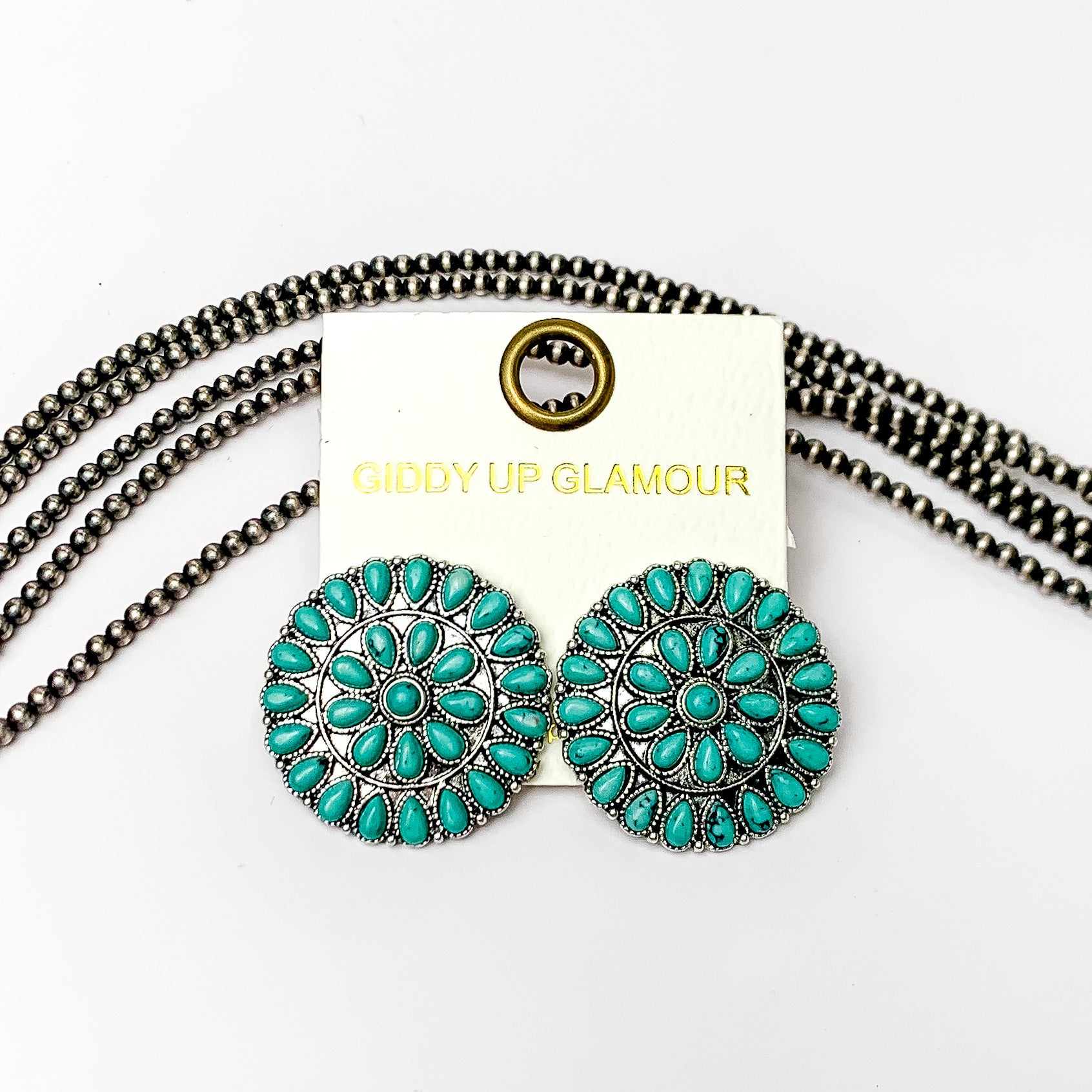 Silver Tone Circle Cluster Stud Earrings with Turquoise Stones. Pictured on a white background with beads behind the earrings. 
