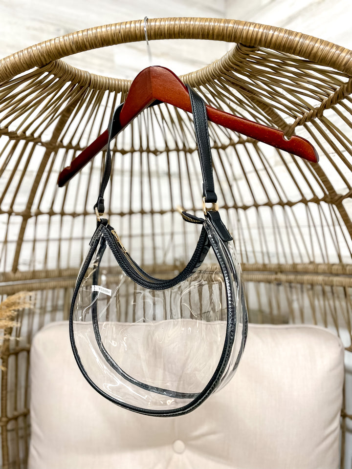 Clear stadium with black trim hanging from a wicker chair on a hanger. 