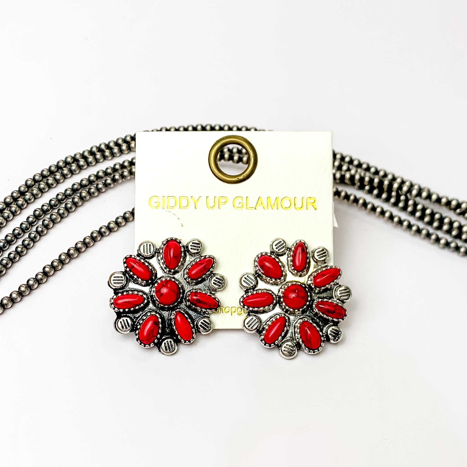 Faux Red Flower Cluster Stud Earrings in Silver Tone. Pictured on a white background with beads behind.