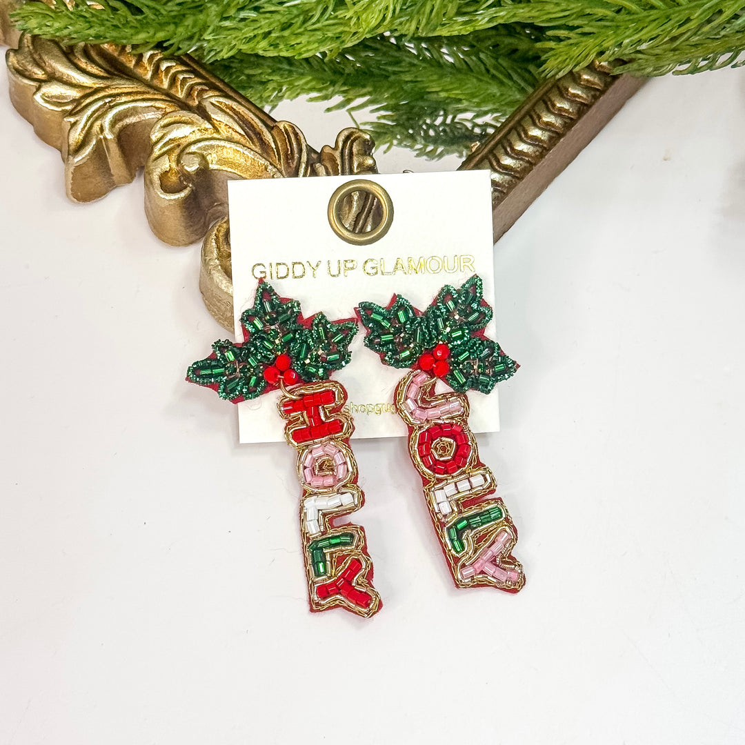 Decorative earrings with 'Merry Christmas' text on a card with 'Giddy Up Glamorous' branding.