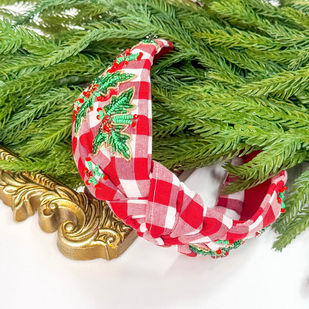 Red and white checkered headband with green holly design on a decorative background