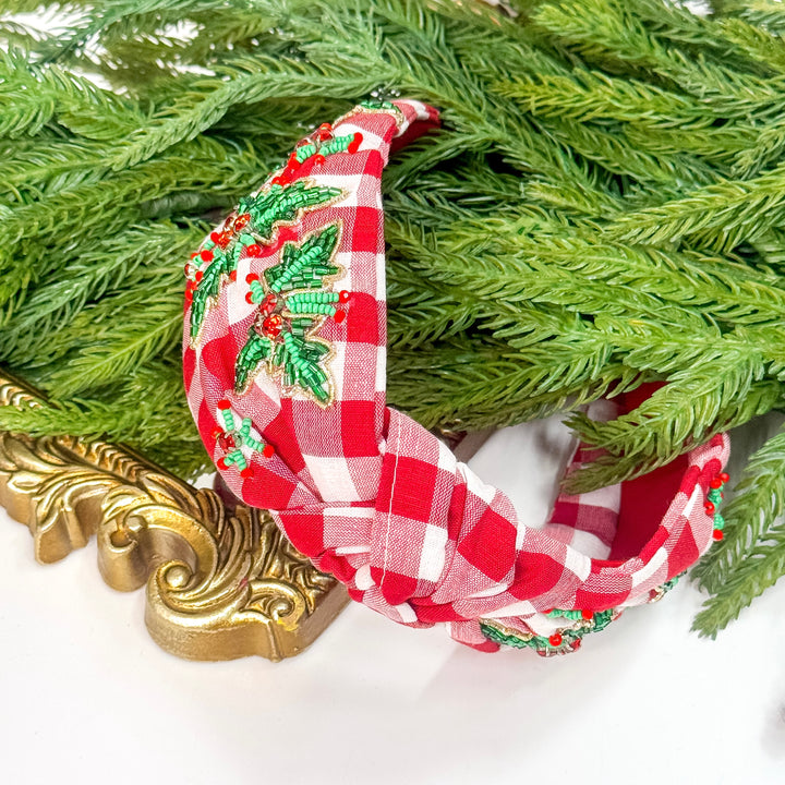Red and white checkered headband with green holly design on a decorative background