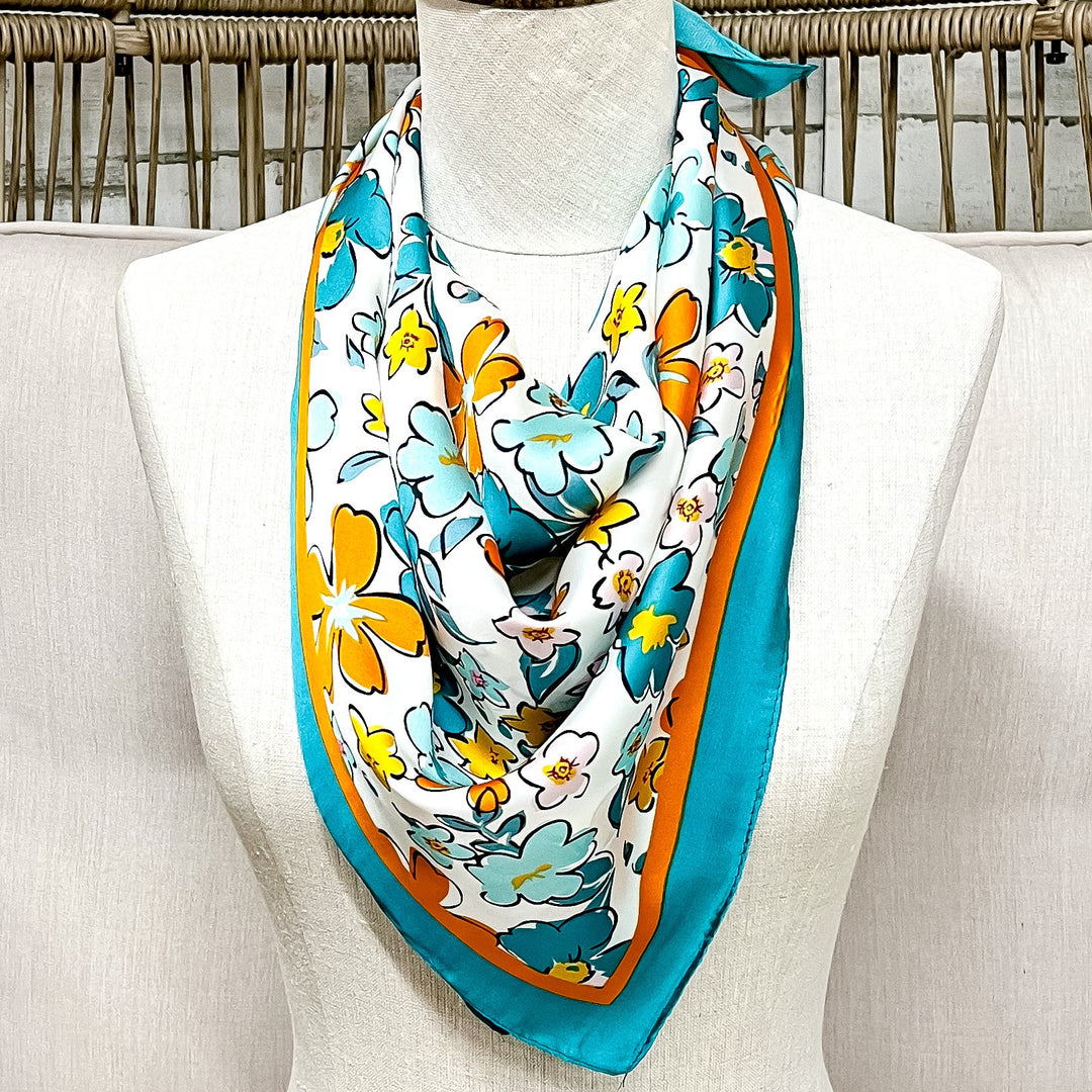 Mannequin head with a colorful scarf draped over it, sitting on a white cushioned chair with a wicker back.