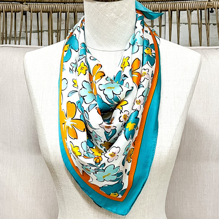 Mannequin head with a colorful scarf draped over it, sitting on a white cushioned chair with a wicker back.