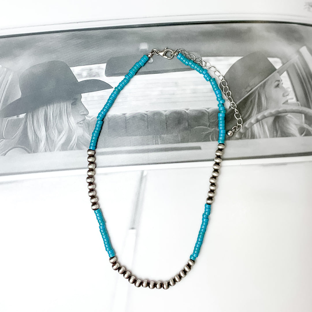 Turquoise chip beaded necklace with faux Navajo pearls there are about nine next to each other on each side and one at the bottom.  Pictured on a black and white photo.