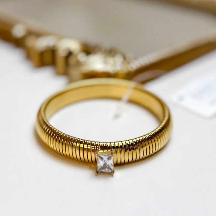 ChanSutt Pearls Mack Stretch Bracelet with Crystal Detail in Gold featuring a ribbed gold-tone stretch band with a princess-cut clear crystal centerpiece.